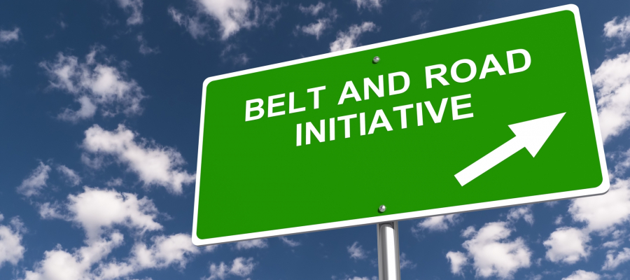 groen bord met in witte letters de tekst Belt and Road Initiative tegen een blauwe lucht met witte wolken