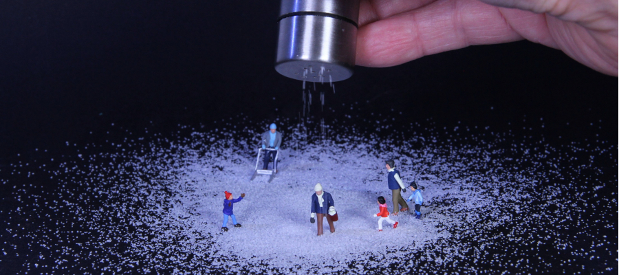 hand strooit zout over miniatuurpoppetjes om sneeuwlandschap te creëren