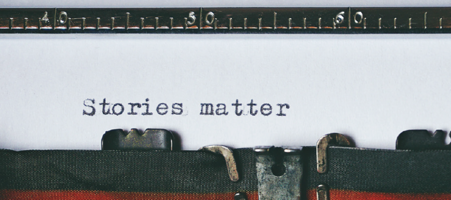 Het bovenste deel van een typmachine. Op een wit blad staat getypt: stories matter.