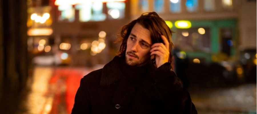 foto van de dichter Jonas Bruyneel 's nachts wandelend door een stad, luisterend met zijn smartphone aan zijn oor 