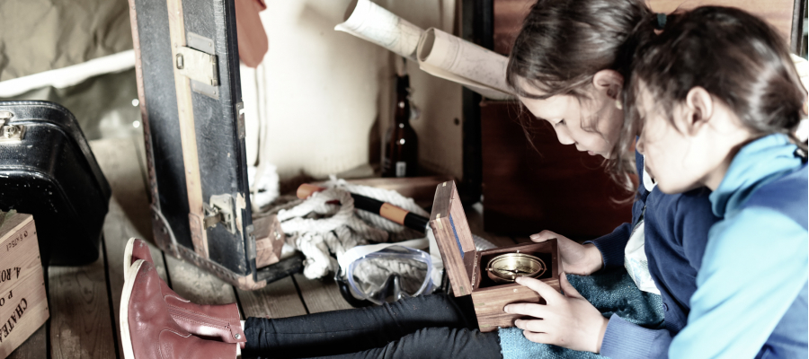twee meisjes spelen met een oud kompas in een houten doosje