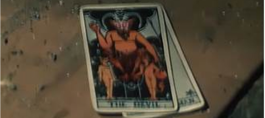 Still uit de documentaire Paradigma. twee (tarot)kaarten liggen op een tafel. Op de bovenste kaart staat een duivel afgebeeld.