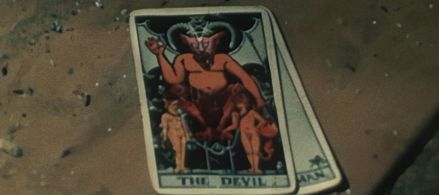 Still uit de documentaire Paradigma. twee (tarot)kaarten liggen op een tafel. Op de bovenste kaart staat een duivel afgebeeld.