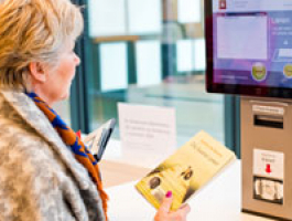 foto: dame scant haar boeken aan de uitleenautomaat