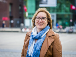 Portret van de ombudsvrouw op straat met op de achtergrond heet wazig de kubus en permeke.