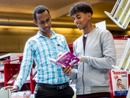 twee jongemannen kijken samen in een boek in de bibliotheek