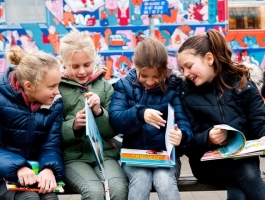 zes kinderen met jas aan kijken blij in boekjes